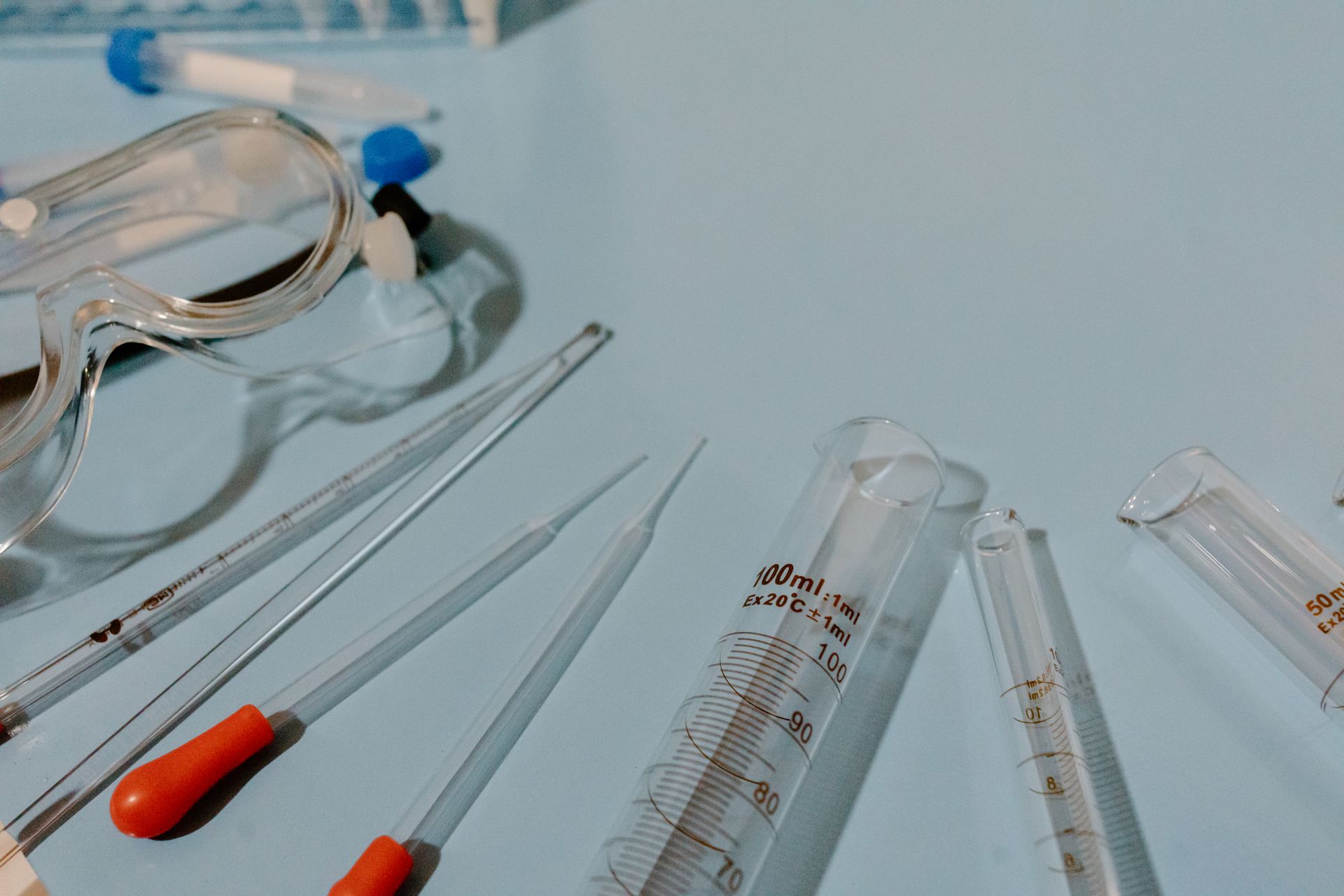 Detailed view of lab equipment like test tubes and goggles on a blue surface.
