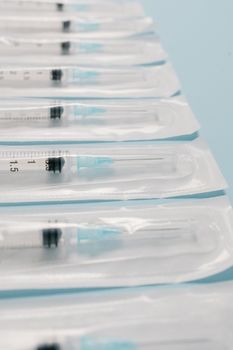 High-quality image of sterile packed syringes perfectly aligned on a blue background, highlighting medical preparedness.