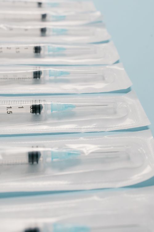 Free High-quality image of sterile packed syringes perfectly aligned on a blue background, highlighting medical preparedness. Stock Photo