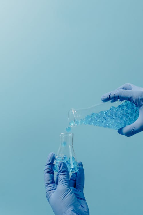 Person in White Gloves Holding Clear Glass Bottle