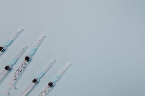 Free Close-up of multiple syringes on a blue background, featuring ample copy space. Stock Photo