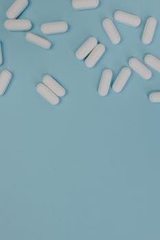 White pills scattered on a blue surface, ideal for medical and pharmaceutical themes.