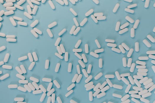 Top view of scattered white pills on a blue surface, representing healthcare and medicine.