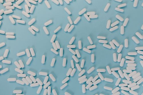 Free Top view of scattered white pills on a blue surface, representing healthcare and medicine. Stock Photo
