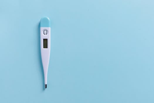 Close-up of a digital thermometer on a light blue background with copyspace.