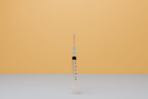 Close-Up Shot of a Syringe on White Surface