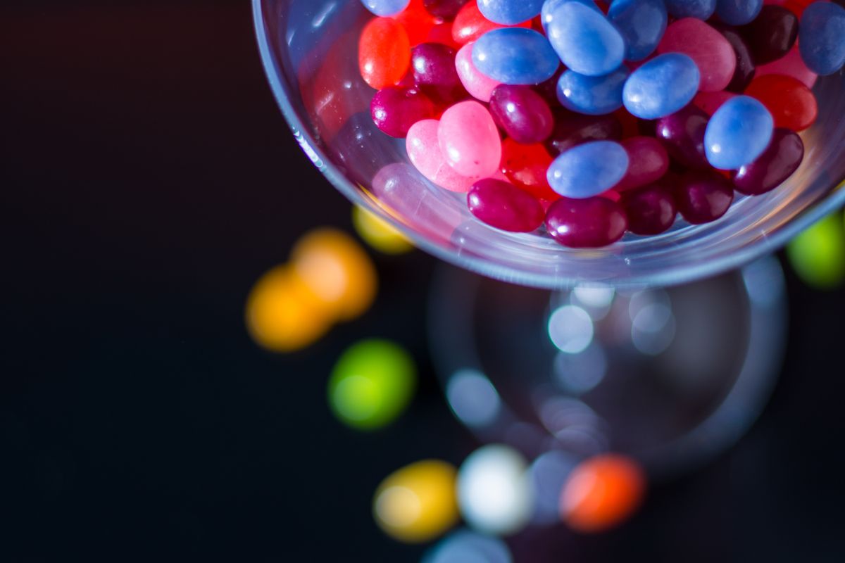 Vibrant close-up of colorful jelly beans inside a cocktail glass with bokeh effect.