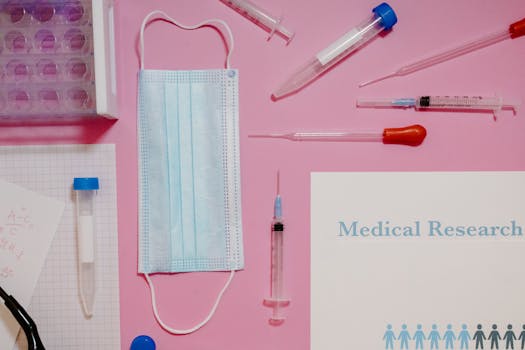 Flat lay of medical research tools and supplies on a pink background.