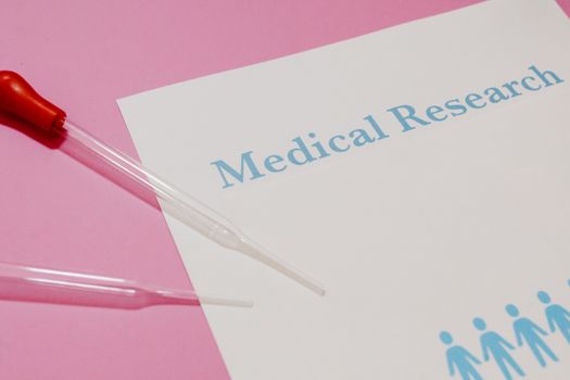 Close-up of a medical research document and pipette on a pink surface, highlighting scientific research and healthcare.