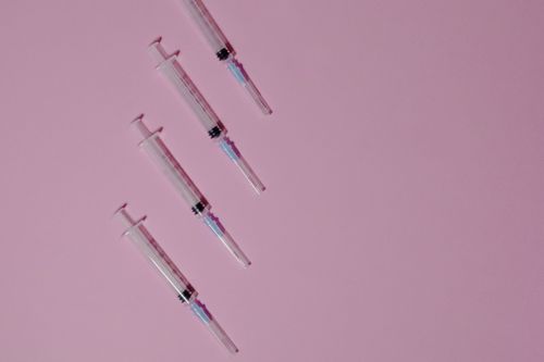 Free Four syringes arranged on a pink pastel background, ideal for medical themes. Stock Photo