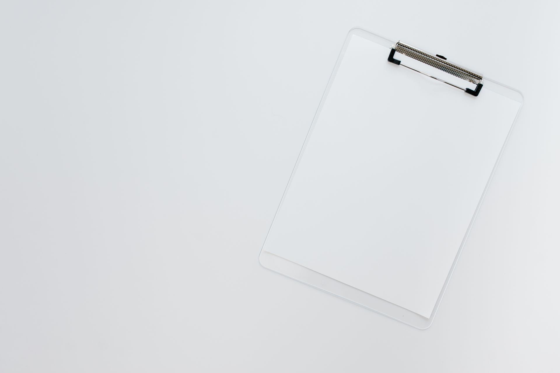 Minimalist top view of a transparent clipboard on a white background offering ample copy space.