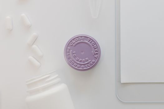 Close-up of a medicine bottle cap with pills on a white background, ideal for healthcare themes.