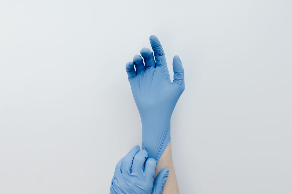 Hands putting on blue nitrile gloves