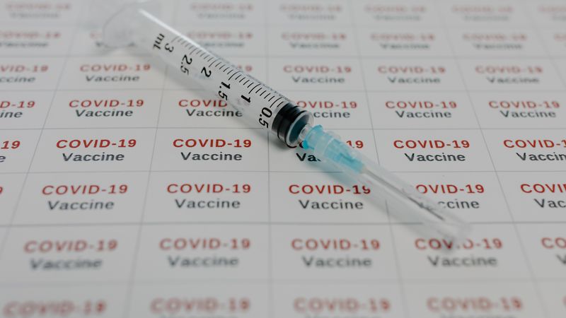A syringe on COVID-19 vaccine labels, symbolizing medical research and vaccination efforts.