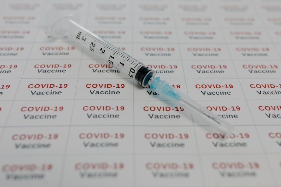 A syringe on COVID-19 vaccine labels, symbolizing medical research and vaccination efforts.