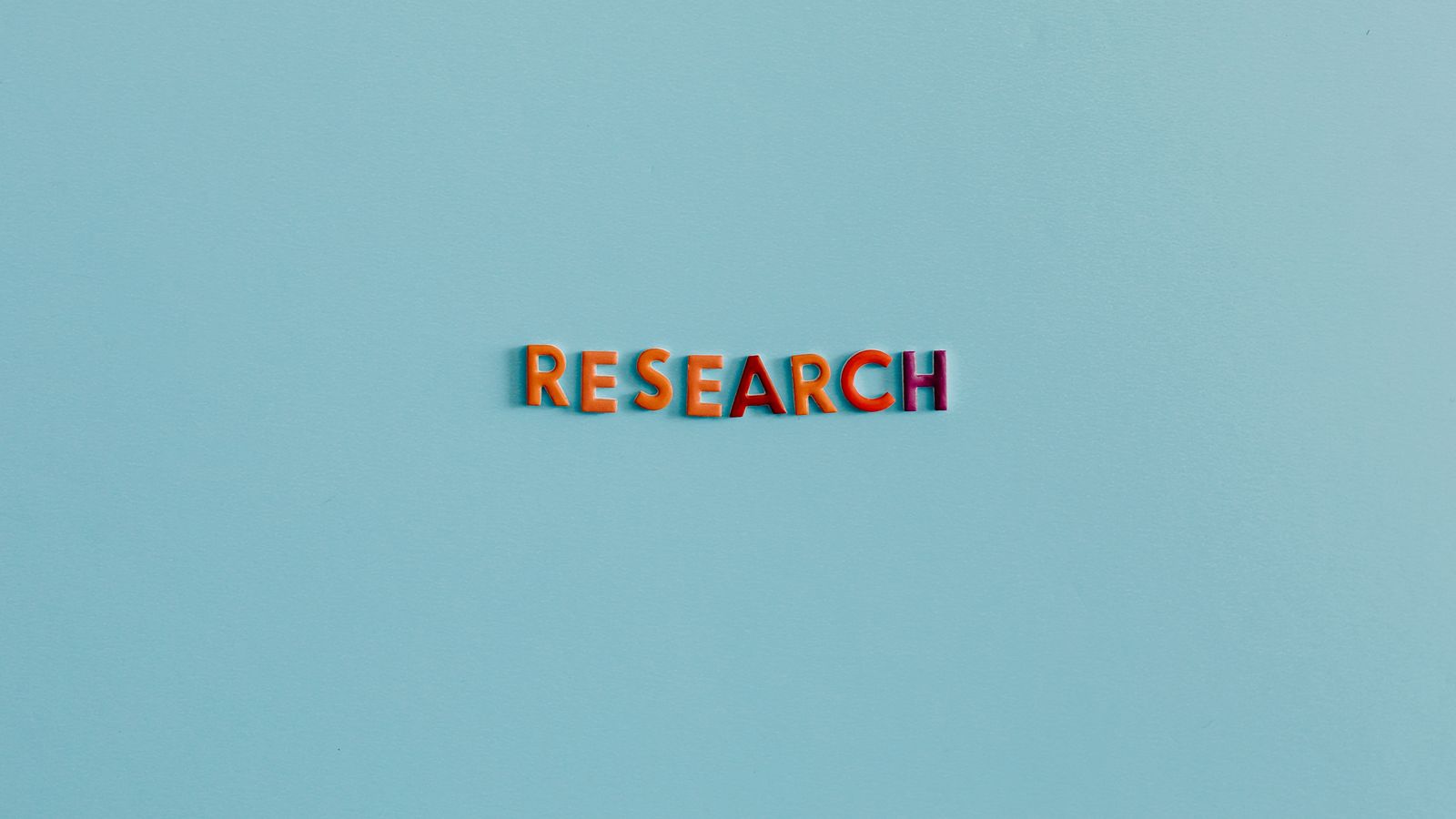 Colorful uppercase letters spelling 'RESEARCH' on a soft blue background. Ideal for education and science topics.