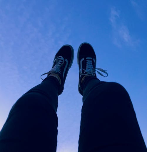 Free Person Wearing Vans Old Skool Sneakers Raising His Feet Pointing to They Sky Stock Photo