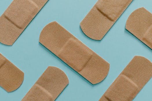 A minimalist flat lay of adhesive bandages on a blue background, perfect for health and treatment themes.