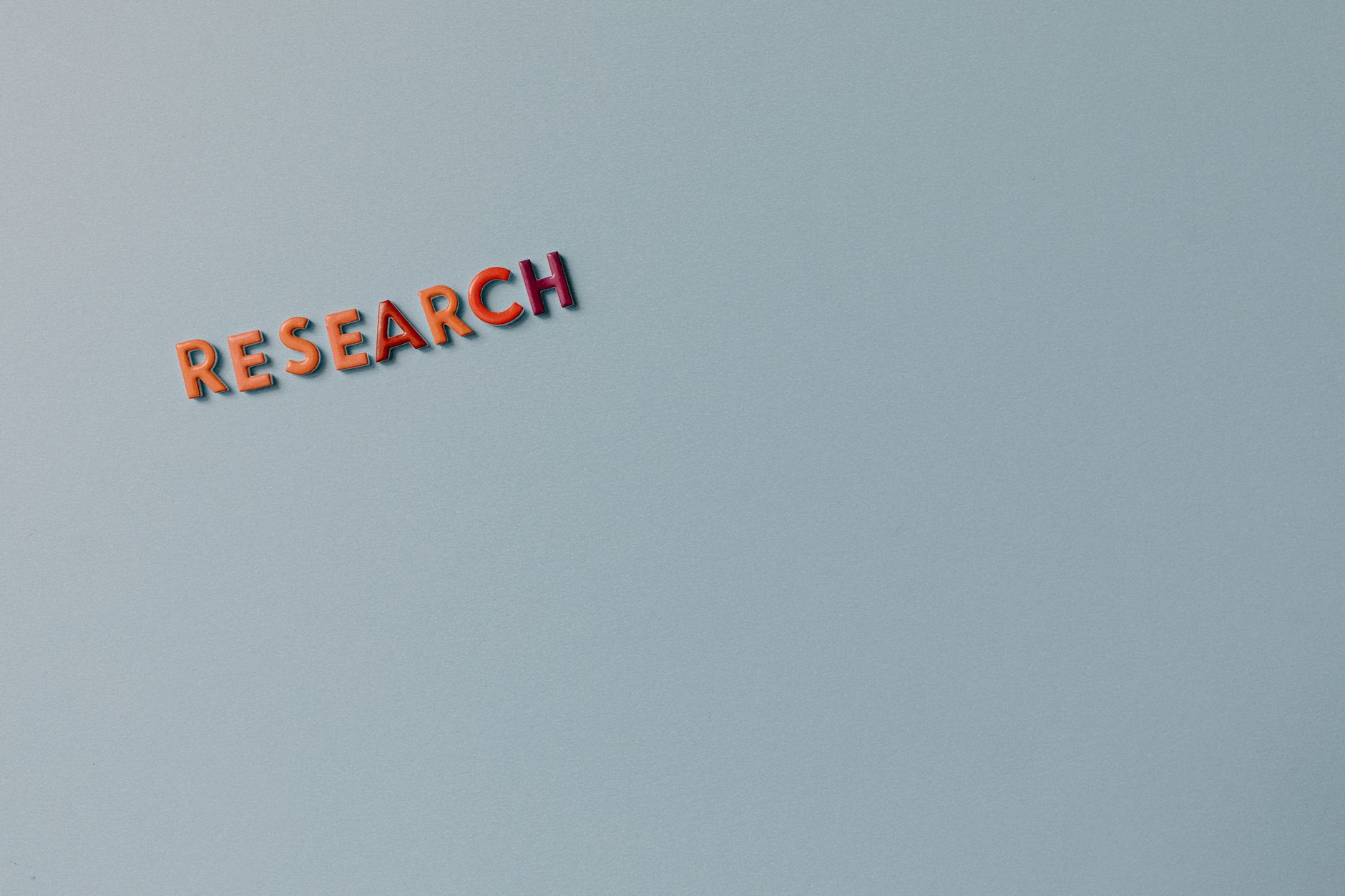 keyword research untuk pemula - Minimalist image with the word 'RESEARCH' in colorful letters on a plain background.