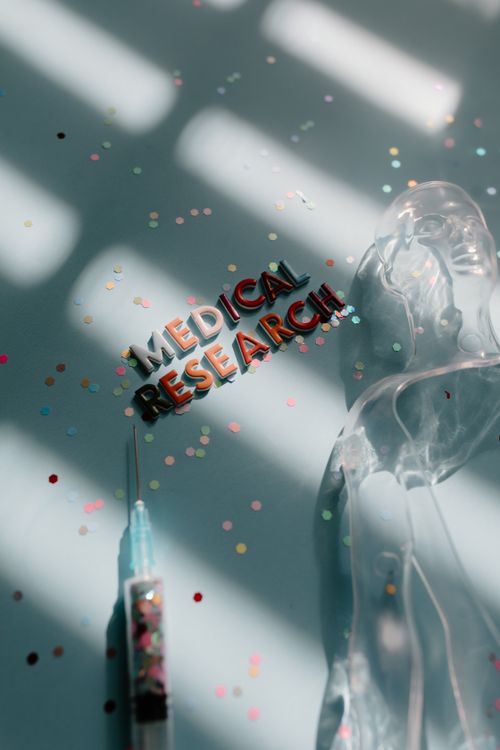 Free Creative depiction of medical research with syringe and confetti on a blue background. Stock Photo