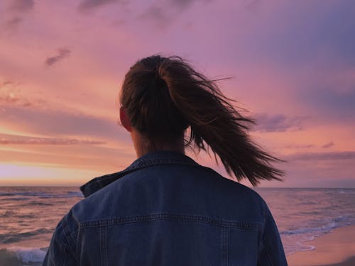 Free Woman Wearing Blue Denim Jacket Looking At The Beach Stock Photo