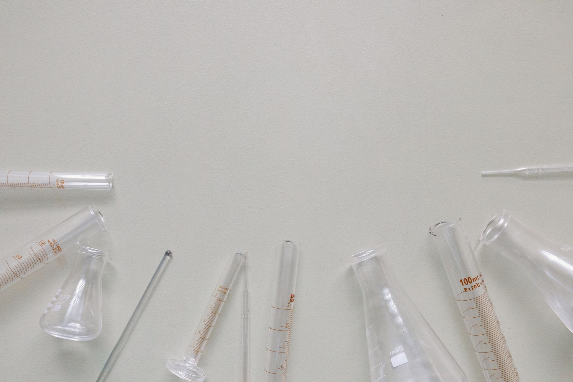 Flat lay of laboratory glassware including beakers and flasks on a neutral surface.