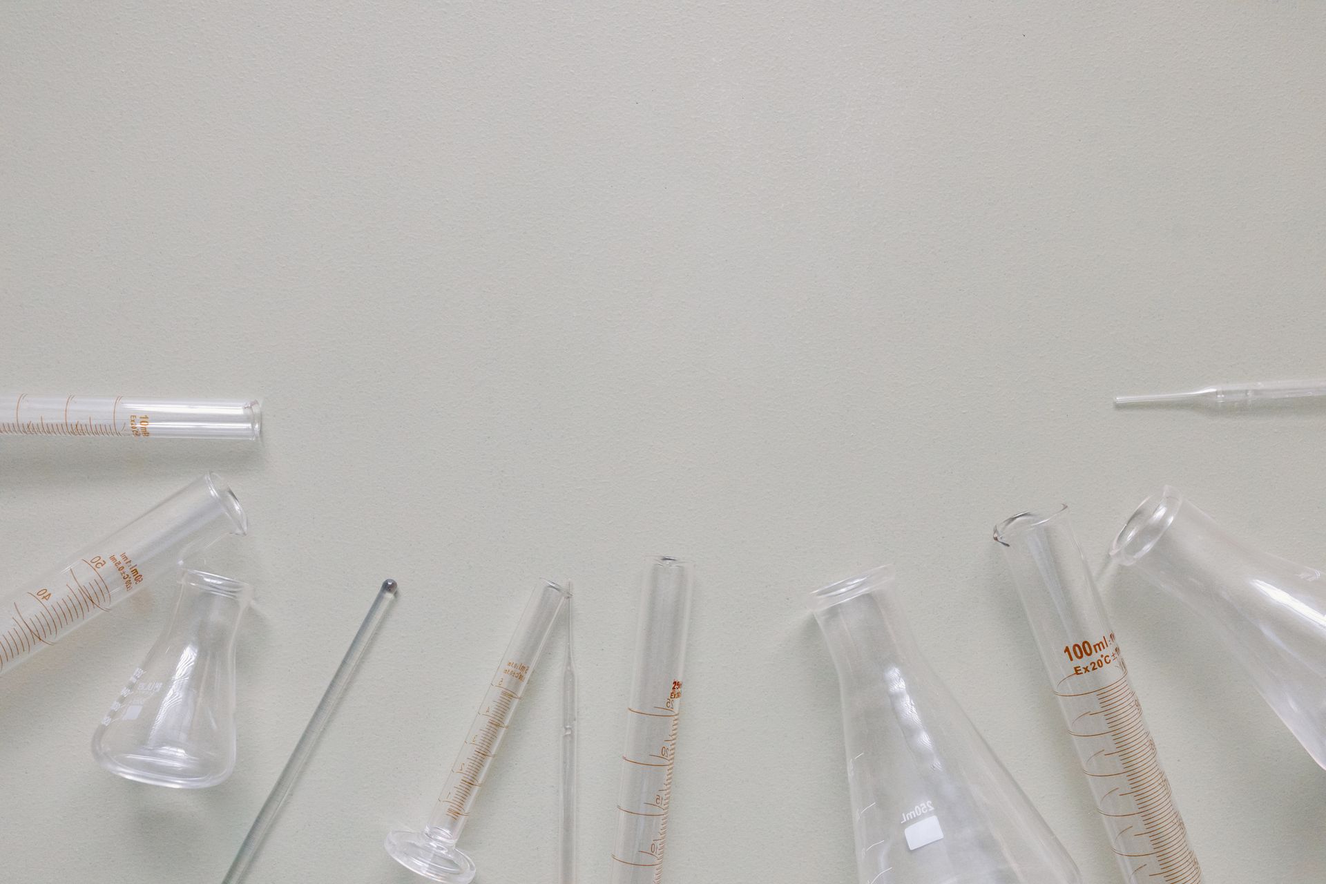 Flat lay of laboratory glassware including beakers and flasks on a neutral surface.