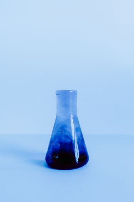 Elegant photo of a laboratory flask with blue liquid in a minimalist setting.