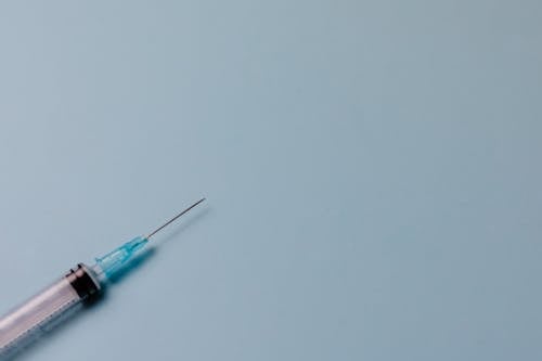 Free Empty Syringe on Blue Surface Stock Photo