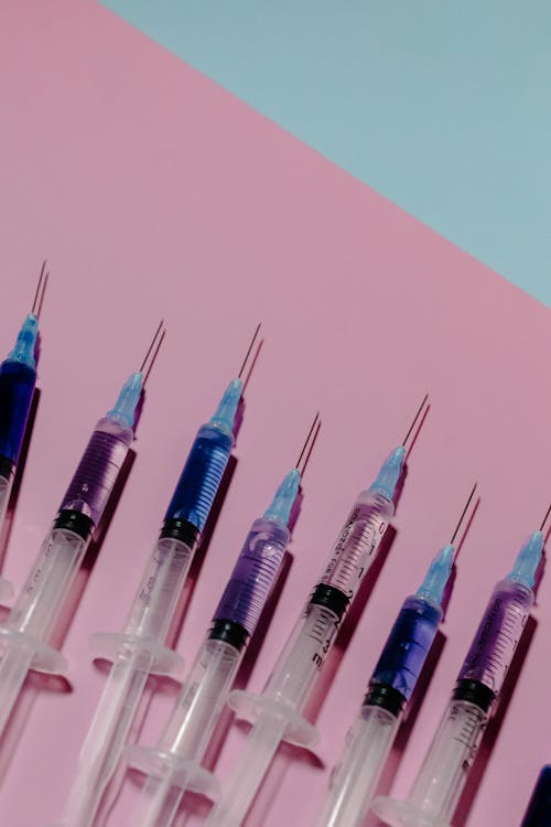 Close-Up Shot of Syringes on Pink Surface