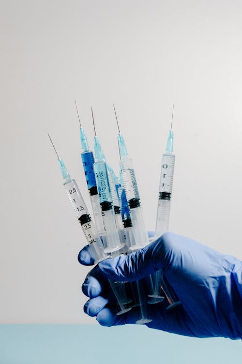 Free Man in Medical Gloves Holding Syringes Stock Photo