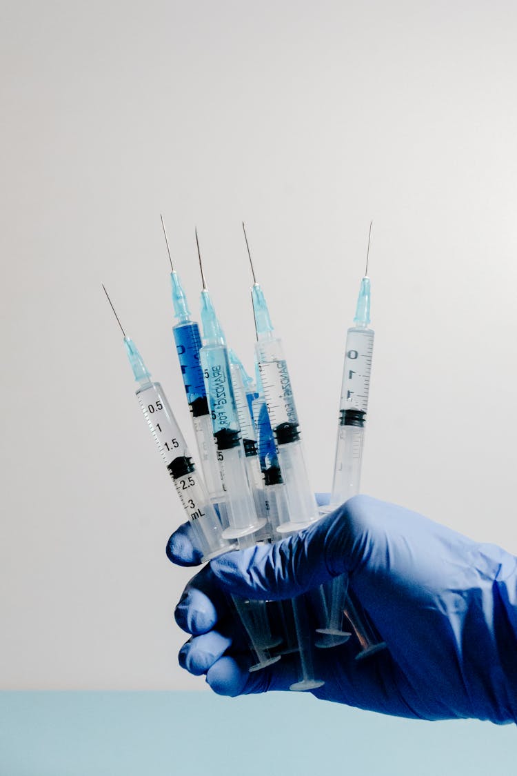 Man In Medical Gloves Holding Syringes