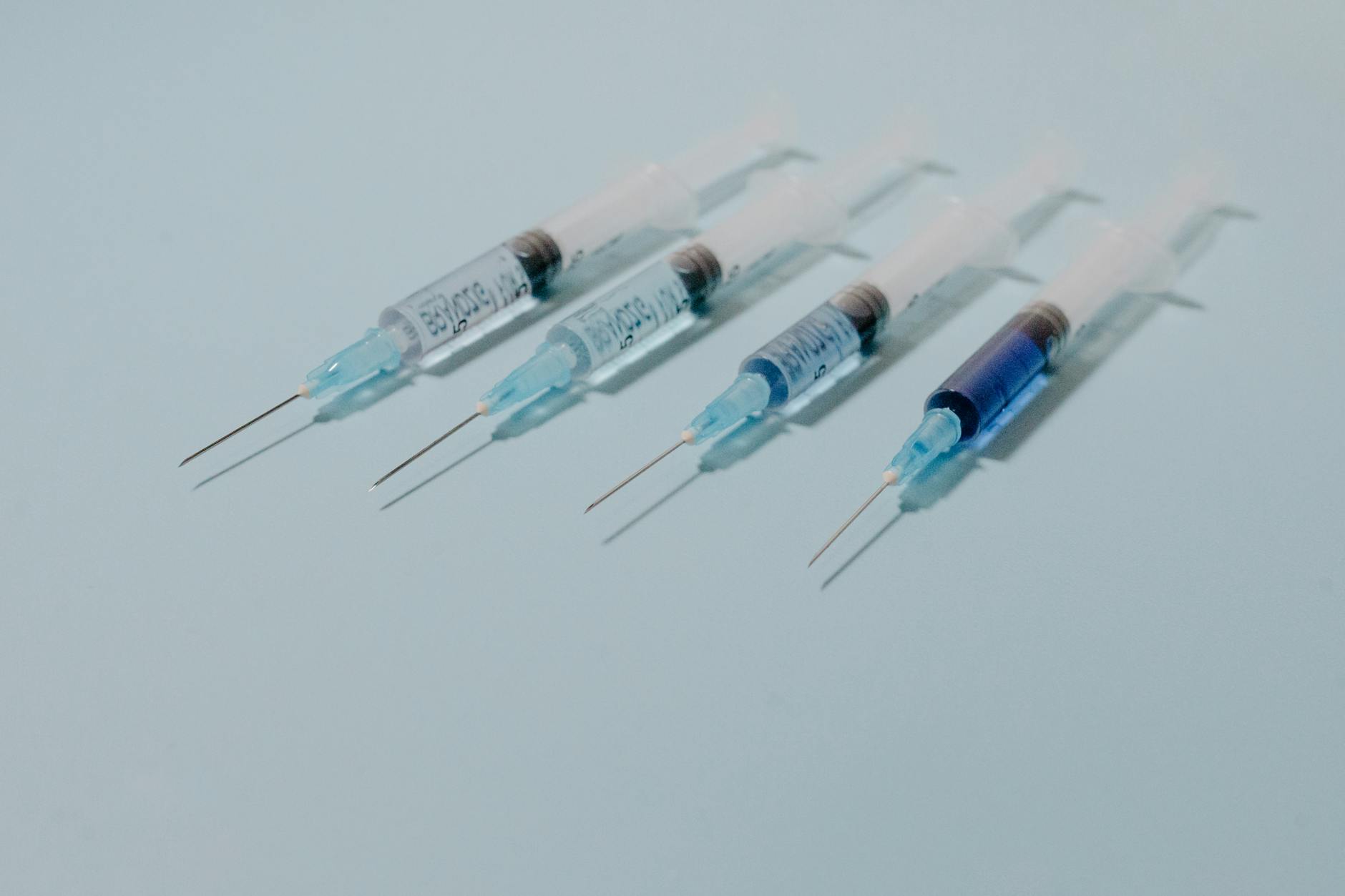 A collection of sterile syringes arranged on a blue surface, ideal for medical themes.