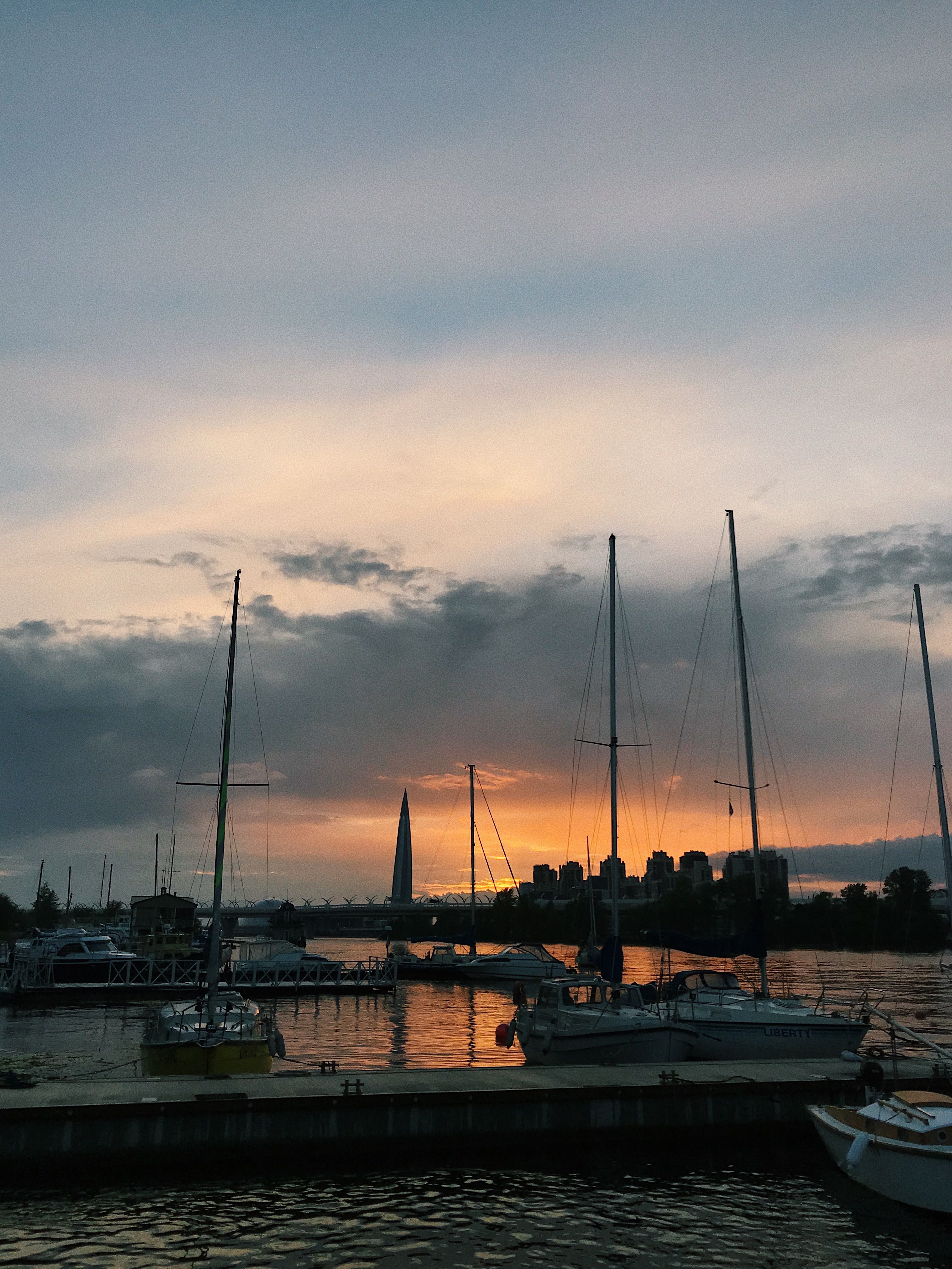 Tranquil sunset at the marina, featuring yachts and sailboats against a vibrant sky.