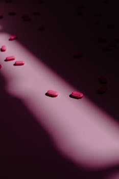 Pink tablets on a surface with dramatic shadow play, highlighting medicine concepts.