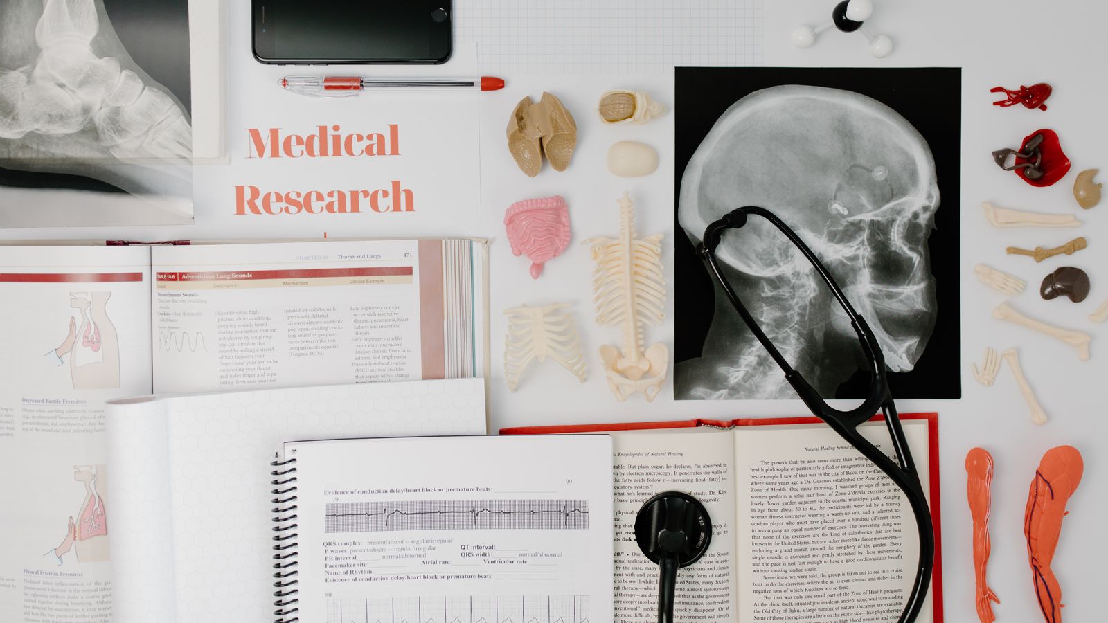 Overhead view of medical research equipment and study materials including books, x-rays, and stethoscope.