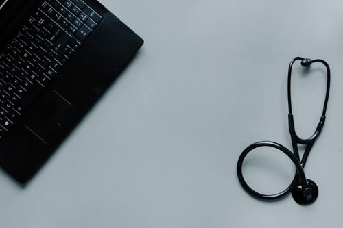 Free Minimalist image depicting a laptop and stethoscope representing telemedicine and digital health. Stock Photo