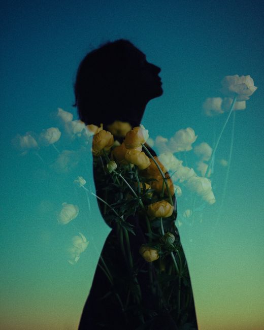 Enchanting double exposure of a woman's silhouette with yellow flowers against sky.