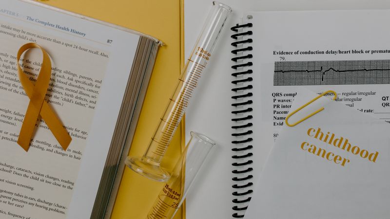 Medical research setup highlighting childhood cancer awareness with a gold ribbon and lab equipment.