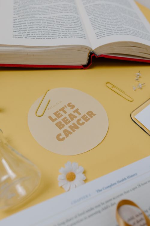 Free Bright workspace with open book, 'Let's Beat Cancer' card, and stationary items for motivation. Stock Photo