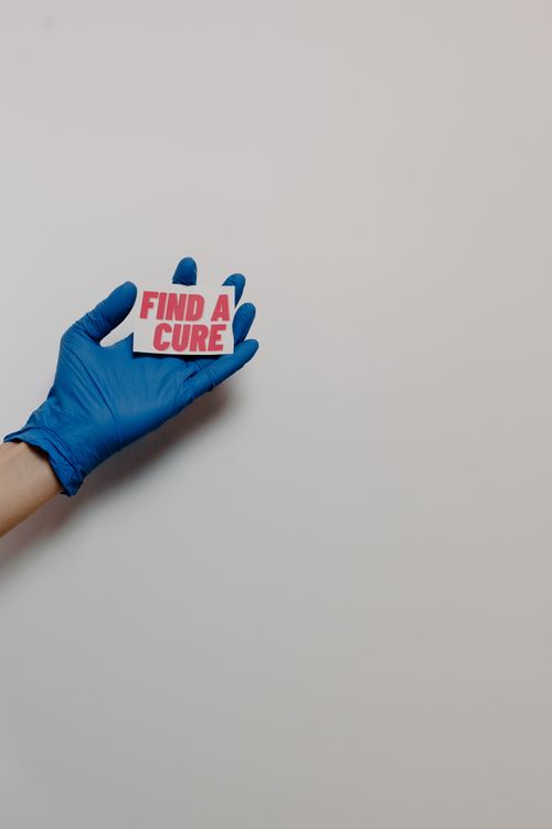 Free A gloved hand holds a card with 'Find a Cure', symbolizing hope and awareness. Stock Photo