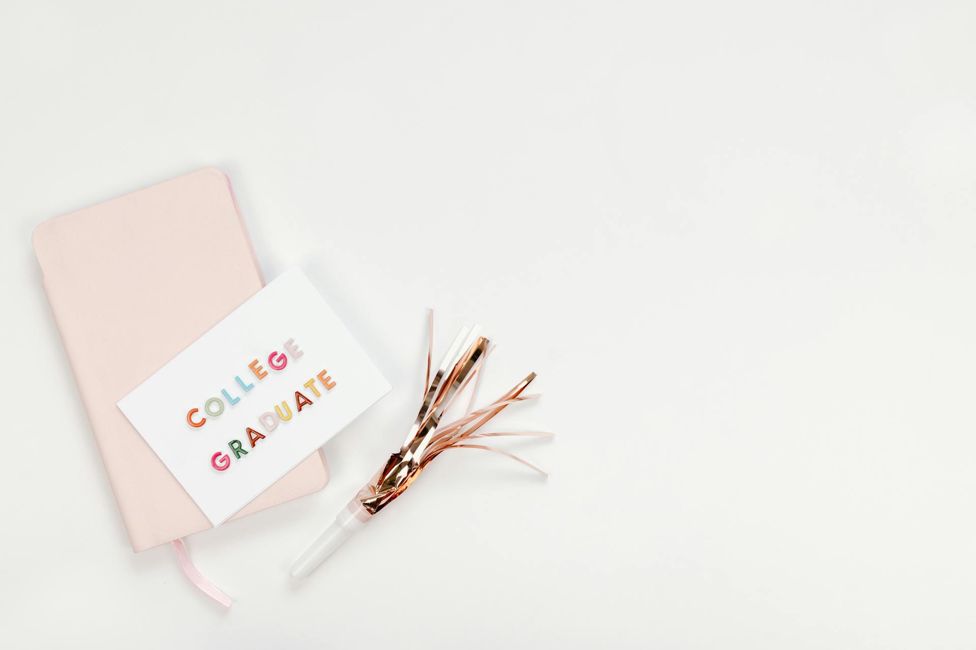 Flat lay of a college graduation card with a notebook and party horn on a white background.