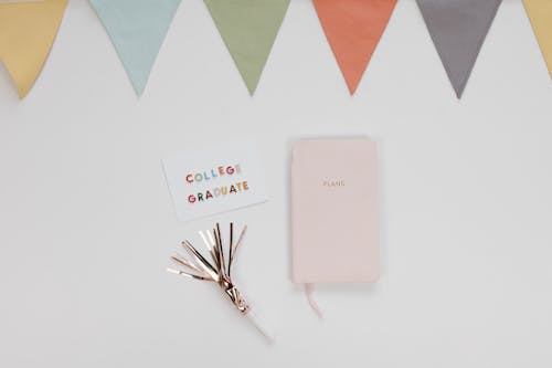 A College Graduate Card Beside a Planner on White Surface