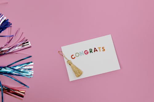 Greeting Card with Tassel on Pink Surface