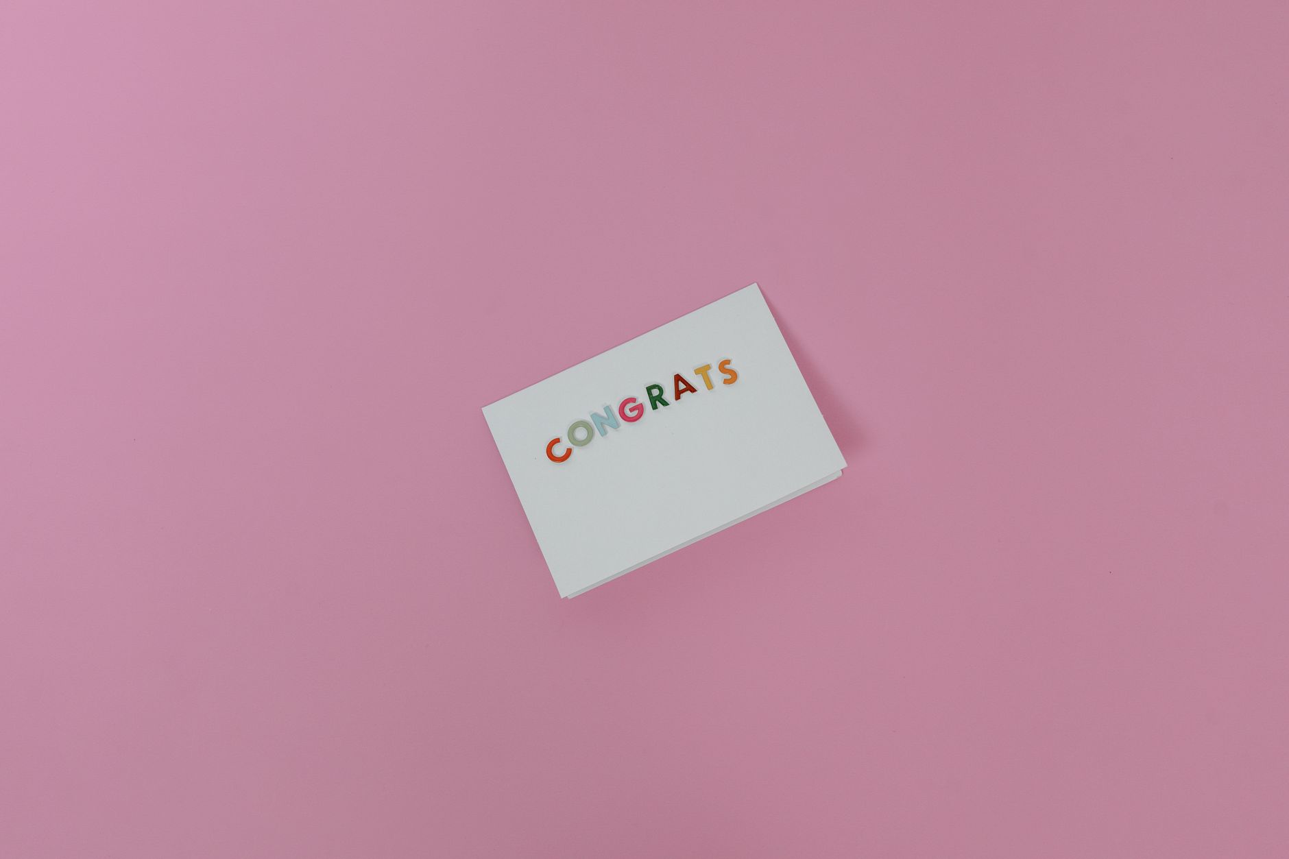 Minimalist congrats card on pink surface, perfect for celebrations.