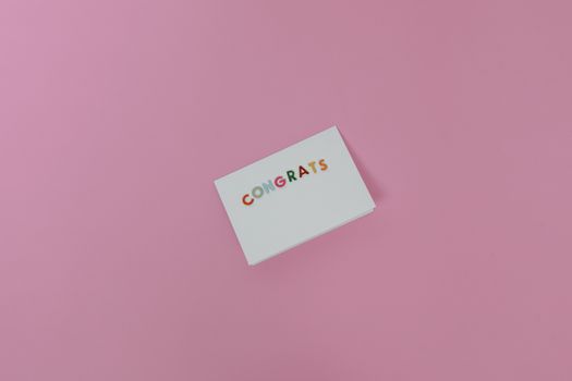 Minimalist congrats card on pink surface, perfect for celebrations.