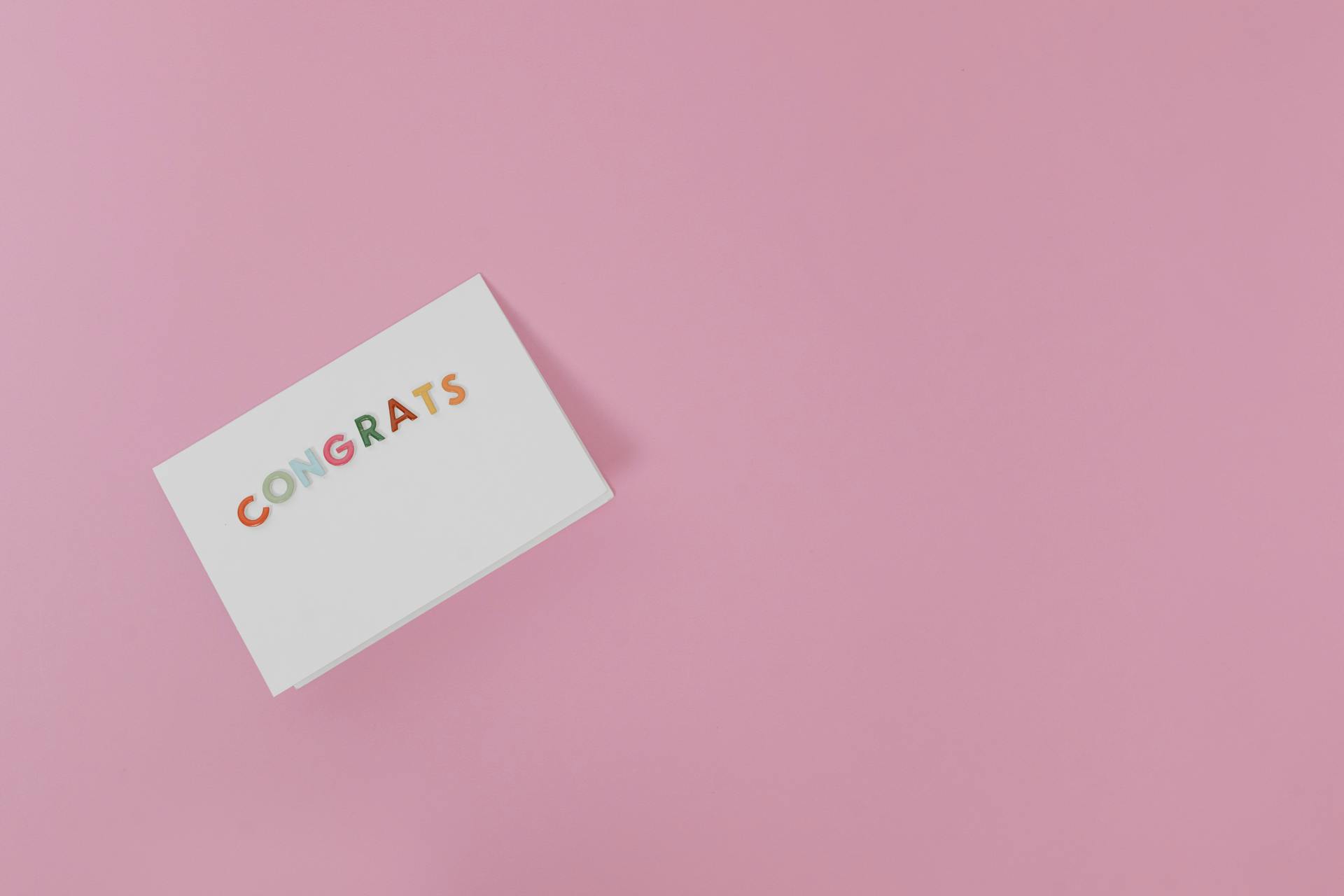 Minimalist congratulatory card on pink background for various occasions.