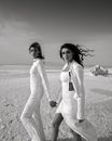 Diverse women in stylish outfits holding hands in desert