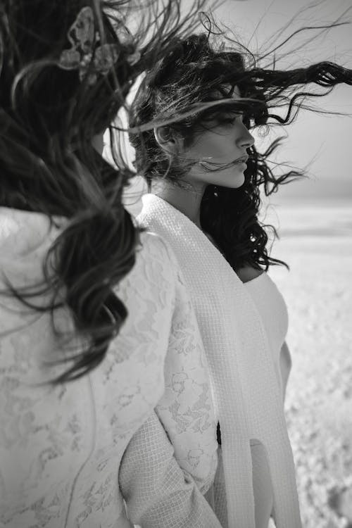 Free Black and white of ladies with long dark hair flying in wind on blurred background of beach Stock Photo