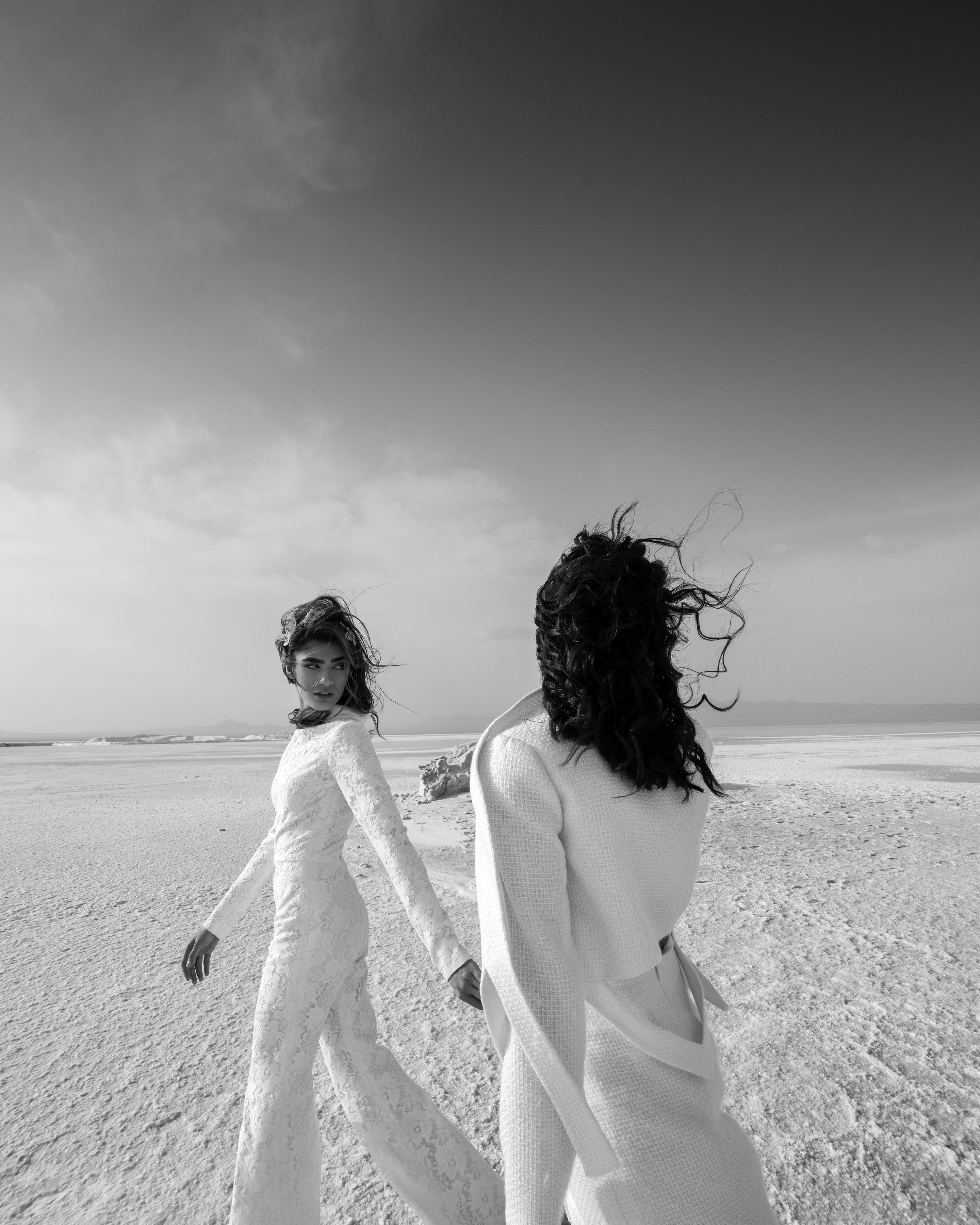 两个穿着白色连衣裙的女人在海滩上享受宁静的一天，捕捉到优雅和自由的感觉